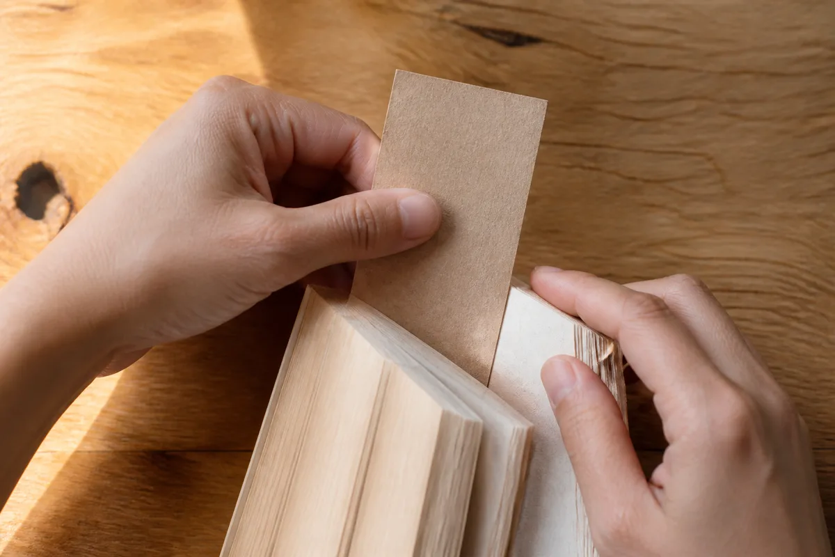 Mains glissant un marque-page en papier kraft dans un roman broché